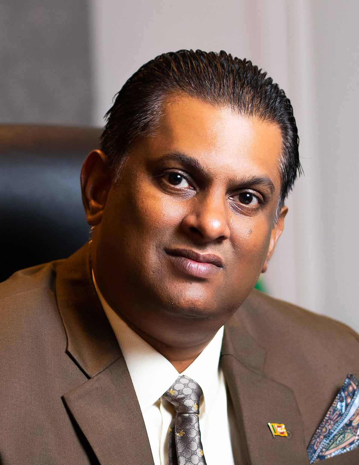 Lawyer in a brown suit looking confidently at the camera, seated in an office setting with a formal backdrop.