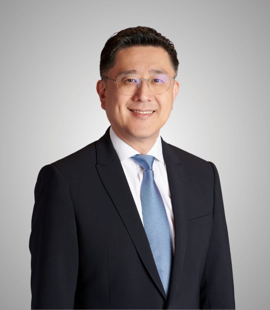 Smiling lawyer in a suit and tie, standing against a neutral background.