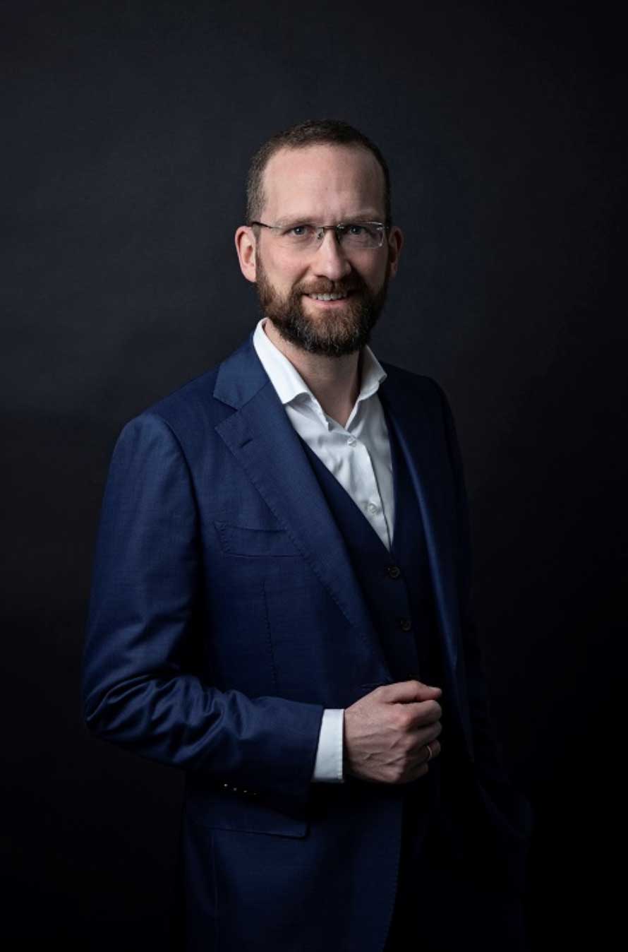 Lawyer in a dark suit, smiling confidently against a black background.