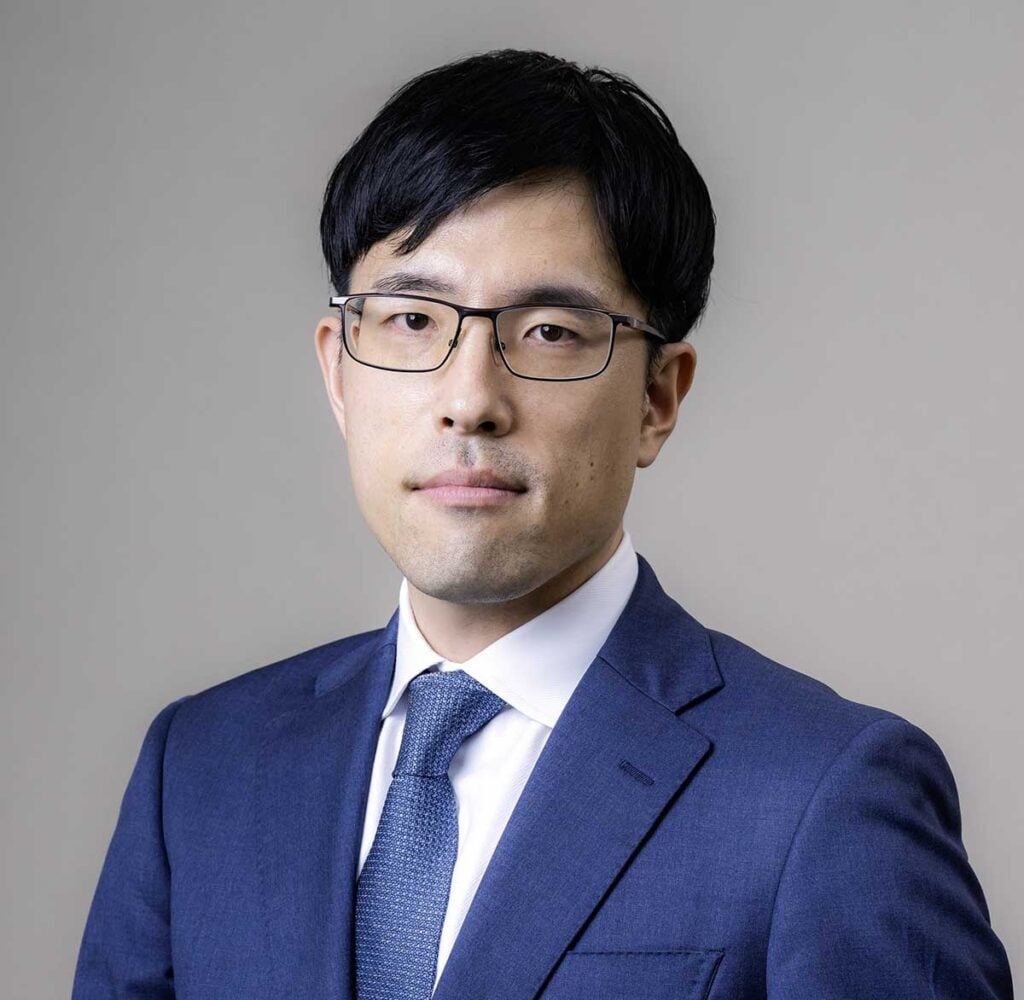 Lawyer in a suit looking confidently at the camera against a neutral background.