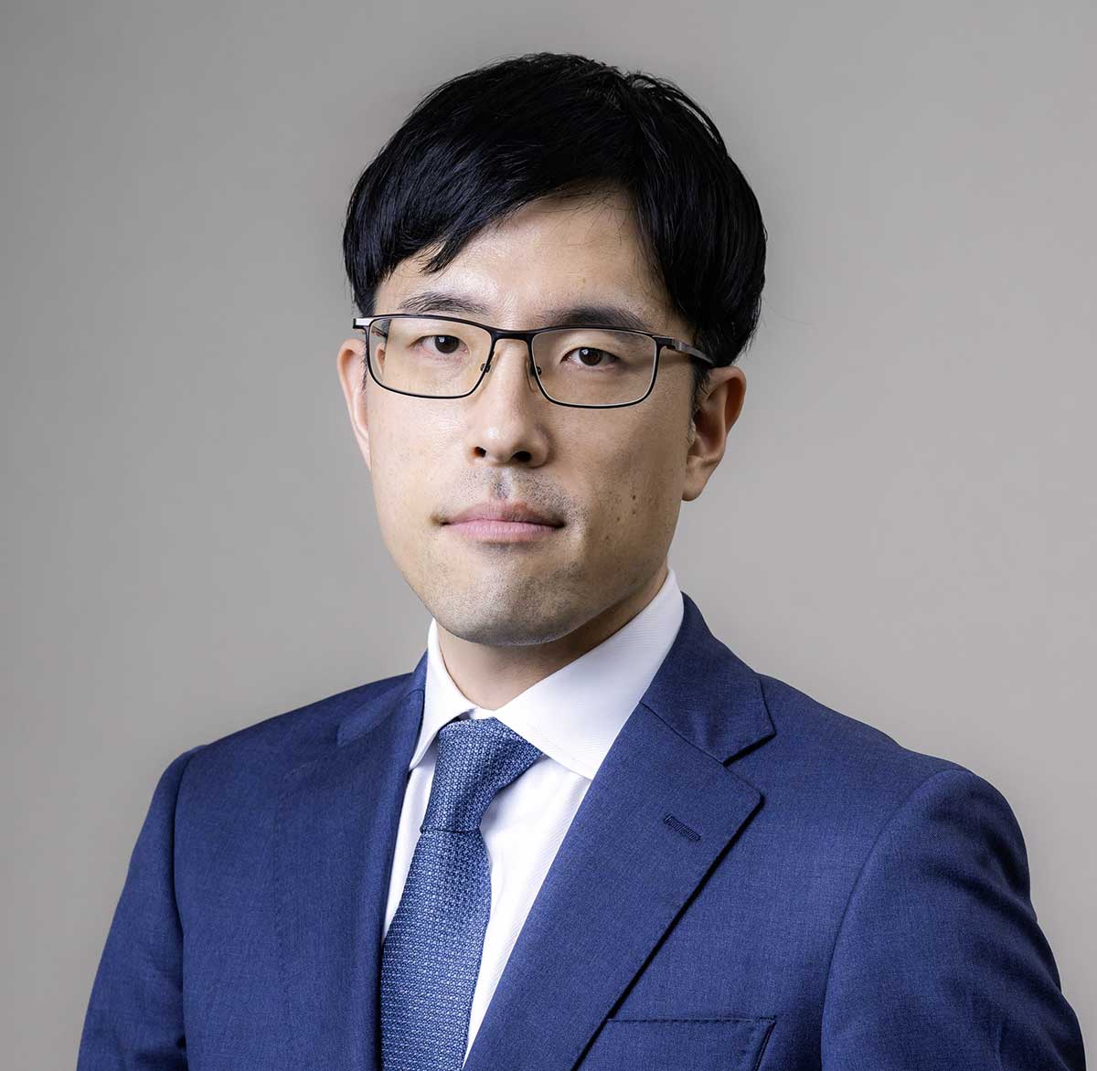 Lawyer in a suit looking confidently at the camera against a neutral background.