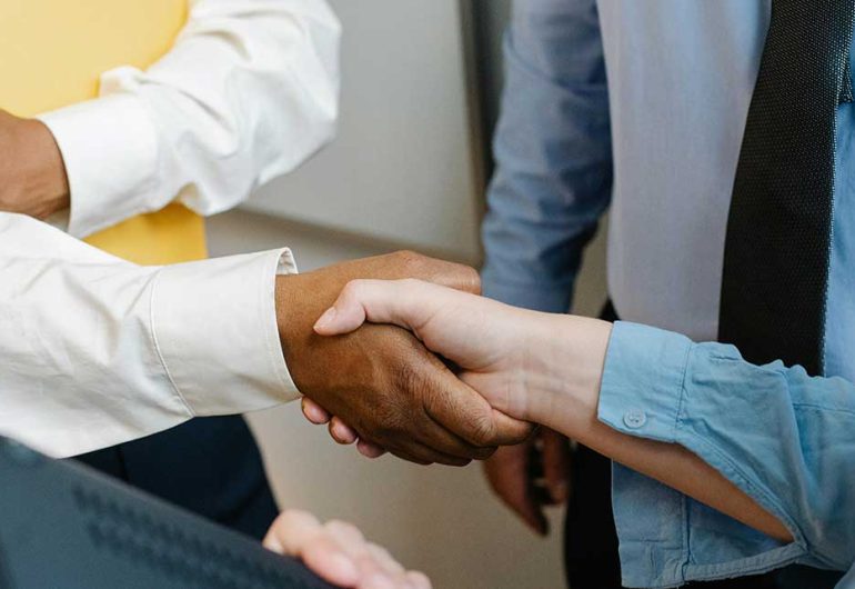 Hands shaking in agreement during a business discussion in a professional setting.