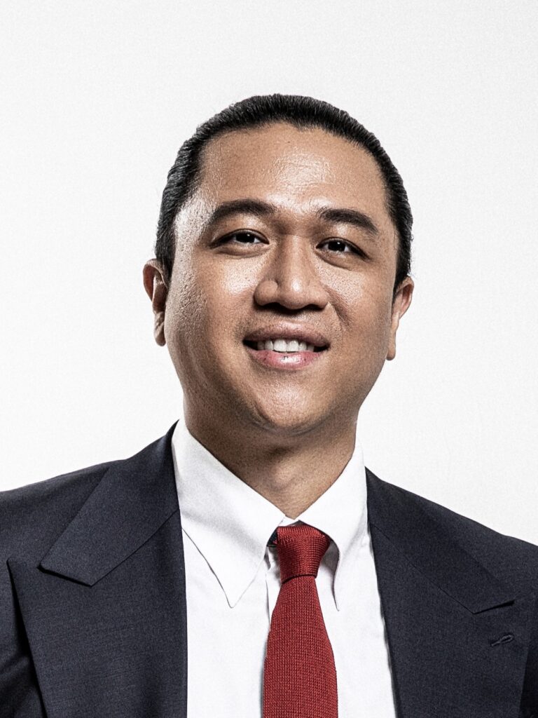 Lawyer in formal attire smiling, posed against a plain background for professional profile.