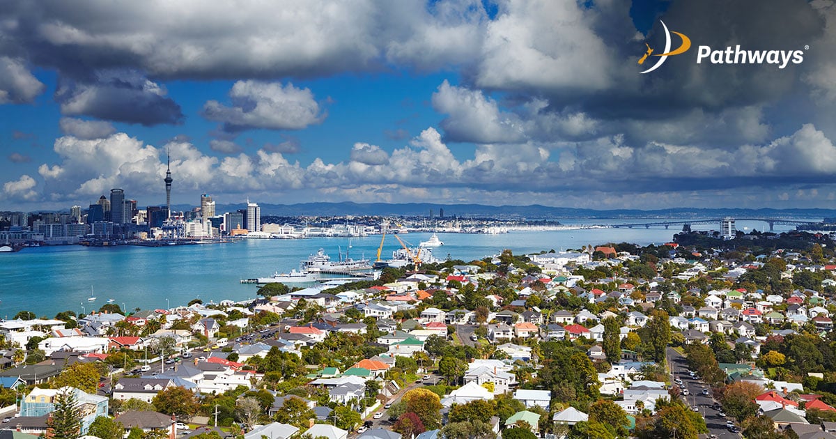 Skyline view of a city by the water, featuring waterfront buildings and boats along the shore.