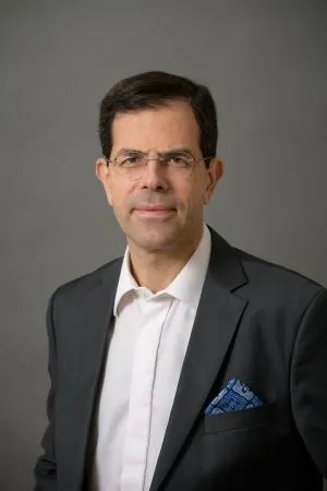 Professional lawyer in a suit, with glasses, posing for a portrait against a neutral background.