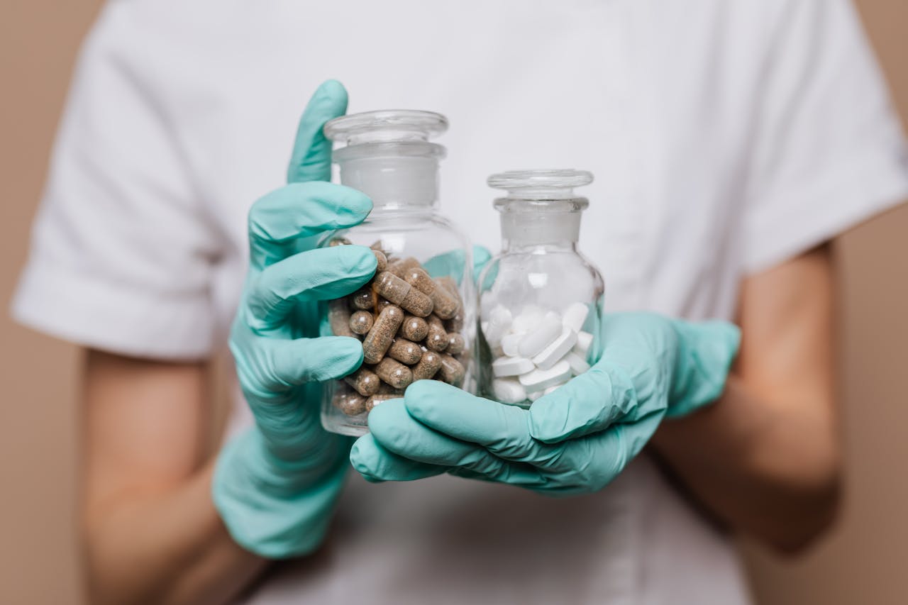 Healthcare professional holding two glass containers with capsules and tablets.