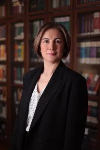 Lawyer posed in front of bookshelves filled with legal texts in an office setting.