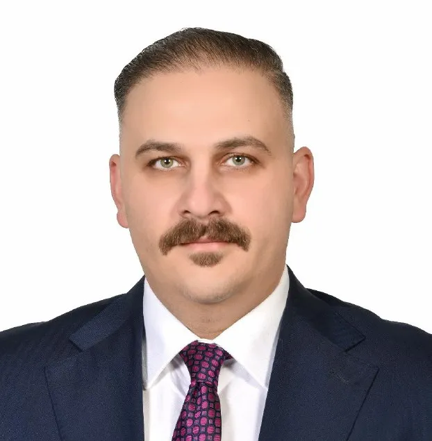Legal professional with a mustache in a suit and tie, framed by a neutral background.