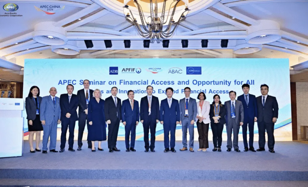 Group of professionals posing at APEC seminar on financial access and opportunity with banners in the background.