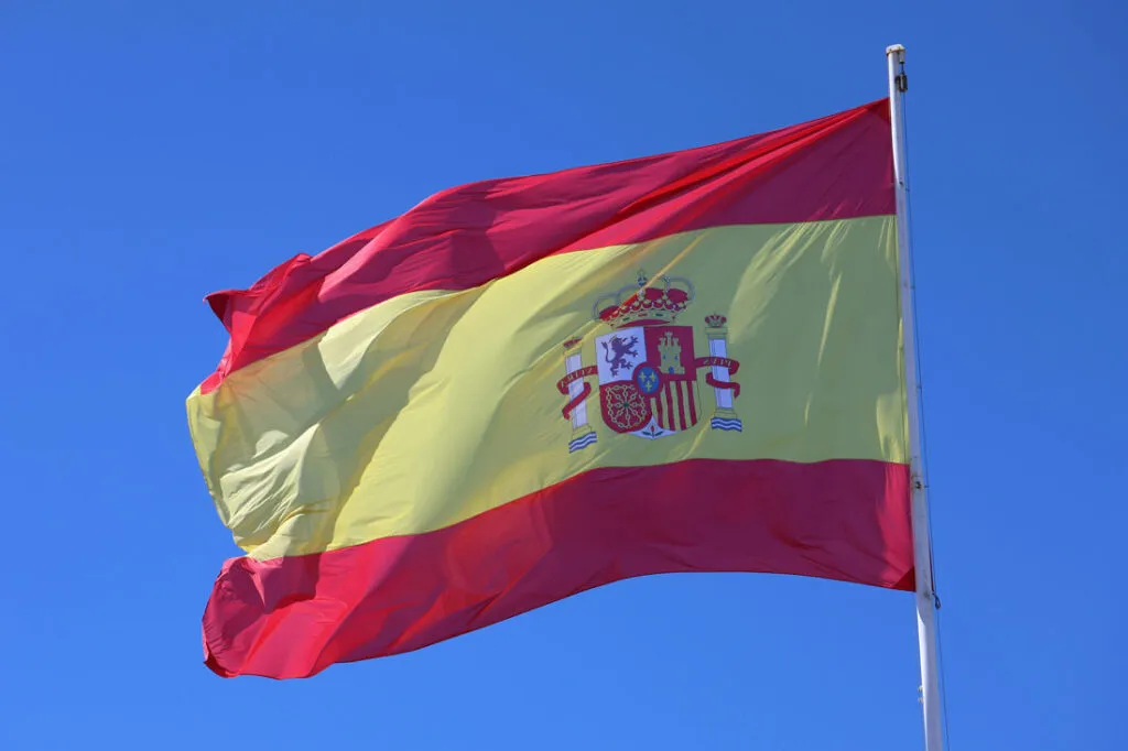 Spanish flag waving against a clear blue sky.