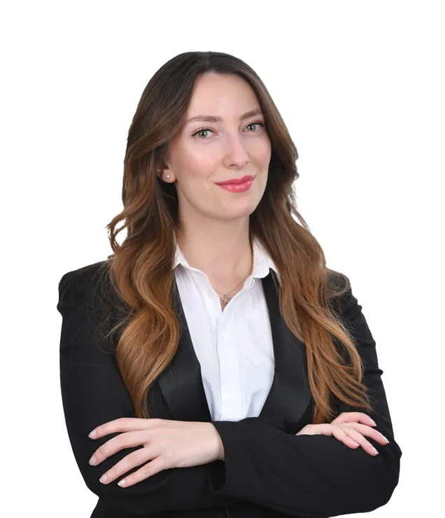 Lawyer in a black suit with arms crossed, smiling confidently against a neutral background.