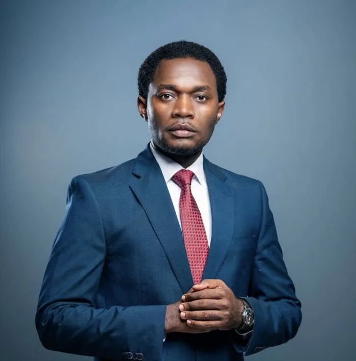 Lawyer in a suit with hands clasped, posing confidently against a neutral background.
