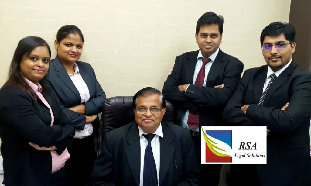 Legal team posed together in law office, with a logo for RSA Legal Solutions visible.