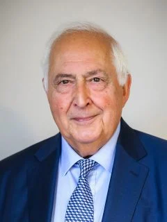 Senior lawyer in a suit, posing with a neutral expression against a light background.