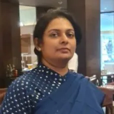 Professional woman wearing a blue saree, standing in a modern office environment.