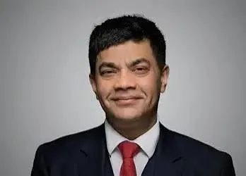Lawyer posing confidently in a suit, smiling at the camera with a neutral background.