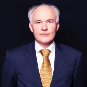 Attorney in suit with yellow tie against a dark background, posing confidently for a professional portrait.
