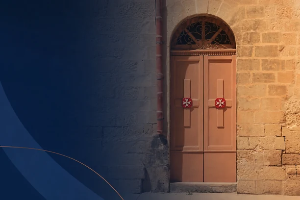 Historic stone wall with decorative wooden doors featuring Maltese cross symbols.