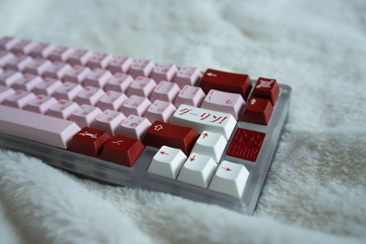 Colorful keyboard with pink and red keys resting on a soft surface.