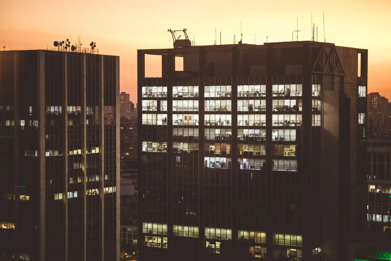 Modern office buildings with illuminated windows at sunset, showcasing various floors and levels.