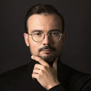 Professional man thoughtfully contemplating with hand on chin against a dark background.